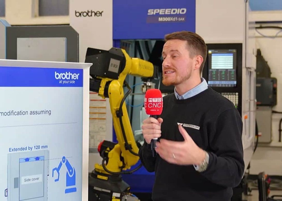 MTD CNC presenter with microphone discussing automation solutions for Brother machining centres at the SECO ITI Event 2026, with a yellow industrial robot and Brother Speedio M300Xd1 in background